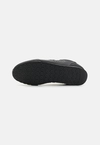 Black athletic shoe sole with circular tread pattern and raised grip areas. Smooth edge design with subtle white accent along the side.
