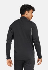 Schwarzes Langarm-Sportshirt mit hohem Kragen, ausgestattet mit grauen Akzenten an den Schultern und Seiten, aus einem glatten, dehnbaren Material gefertigt.