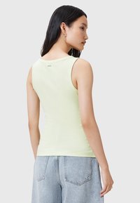 Top sin mangas de color verde claro con un diseño ajustado y una suave textura de algodón. Presenta un escote redondo y un mínimo de marca en la parte posterior.