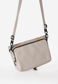 Borsa a tracolla in tessuto grigio con un accento arancione, dotata di zip superiore, tracolla regolabile e chiusura a scatto nella parte inferiore.