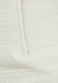 Tessuto bianco con texture, dotato di una cerniera visibile che mette in evidenza il suo motivo intrecciato e il dettaglio della chiusura liscia.
