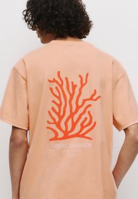 Tricou din bumbac piersici cu un grafic mare de corali portocalii pe spate, cu textul "GREAT SUMMER Chill Vibes Only" în alb.
