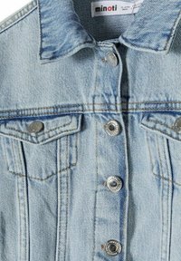 Veste en denim bleu clair avec un col pointu, des boutons-pression argentés et deux poches à rabat sur la poitrine. Texture usée avec des coutures orange.