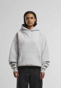 Pelēks kapuce, kas izgatavota no mīksta materiāla, ar plašu priekšējo kabatu, ribotām piedurknēm un oderētu kapuci komfortam.