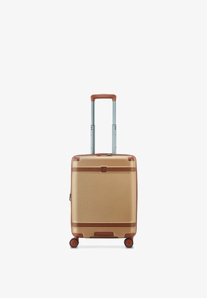Valise rigide compacte dorée avec des accents marron, quatre roues pivotantes et une poignée télescopique déployée.