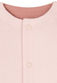 Ljust rosa ribbad topp med rund halsringning, prydd med två beige knappar på framsidan och en mjuk textur. Innerkragen är en något mörkare rosa.