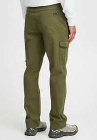 Olive green cargo pants featuring a straight leg design, multiple pockets, and a sturdy cotton material, paired with gray athletic shoes.
