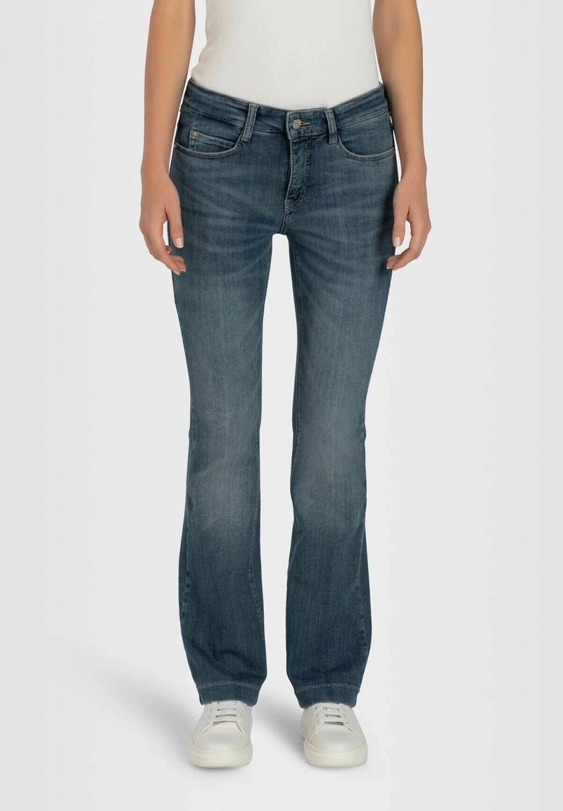 Jean en denim bleu avec une coupe droite, présentant une taille mi-haute, un style à cinq poches et un léger délavage. Portés avec des baskets blanches.