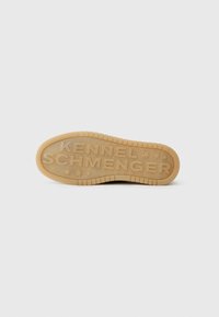 Semelle de chaussure en caoutchouc couleur beige avec un grip texturé. Détails gravés "KENNEL SCHMENGER" et étoiles. Forme plate, finition lisse, bout rond.