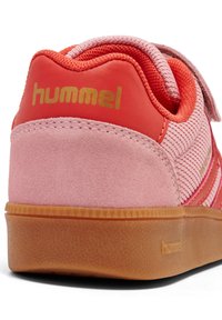 Rosa mocka och mesh sneakers med röda accenter, guldbranding och en texturerad gummisula. Utrustad med kardborrefäste och randig design.