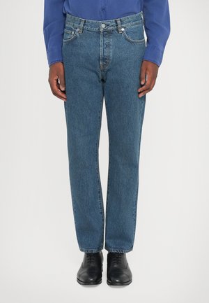 Jeans din denim albastru cu croi drept, având cinci buzunare, închidere cu nasture și bucle pentru curea, asortați cu pantofi de dress negri.
