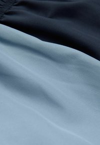 Două bucăți de țesătură care se suprapun: bleumarin închis și albastru deschis. Materialul este neted, cu un ușor luciu, arătând pliuri delicate și textură.
