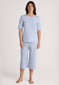 Light blue short-sleeve top with a round neckline, paired with mid-calf pants featuring a white polka dot pattern on a light blue background.