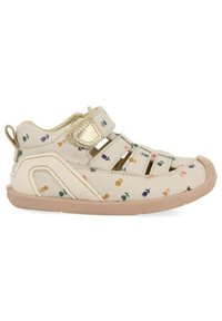 Zapato infantil beige con estampado floral, que cuenta con una correa de velcro, diseño abierto, suela de goma y una puntera texturizada.