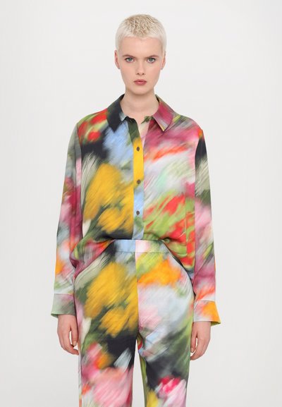 Blouse en soie multicolore et pantalon assorti présentant un motif floral abstrait avec des nuances de rose, jaune, bleu et vert.