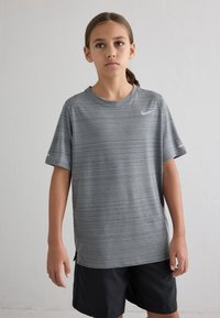 Grå sports t-shirt med vandrette striber, korte ærmer, rund hals og et lille hvidt logo på brystet, parret med sorte shorts.