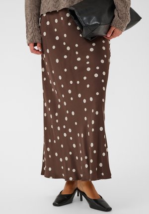 Lange bruine rok met witte stippen, gedragen met zwarte hakken, een bruine trui en een zwarte leren clutch.