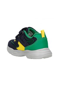 Sneaker avec une tige en tissu bleu marine, des accents verts, des détails jaunes et un col rembourré ; sécurisé par des bandes Velcro et une semelle blanche.