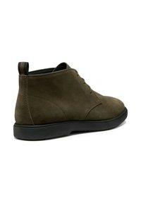 Botines de ante verde oscuro con puntera redondeada, parte delantera con cordones y suela de goma negra. Cuenta con una tira en el talón para facilitar el calzado.