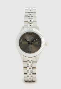 Orologio argento con lunetta scanalata, quadrante grigio scuro, numeri romani e bracciale a maglie metalliche. Logo del marchio ben visibile alle 12.