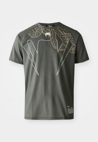 T-shirt à manches courtes vert foncé en tissu lisse, avec un design graphique de serpents entrelacés en or et blanc.