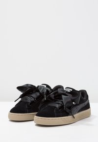 Baskets en daim noir avec des lacets larges en satin noir et une semelle en caoutchouc beige texturée. Marquage sur la languette et le côté.