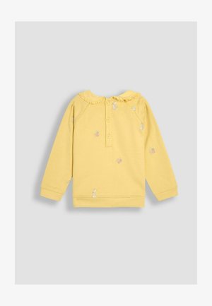 Sárga, hosszú ujjú pulóver fodros gallérral, elöl gombokkal, és hímzett nyuszikkal és virágokkal. Puha pamut anyag, laza szabás.