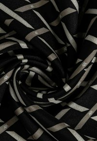 Tessuto nero con un intricato motivo di nastri argentati. Il materiale presenta una superficie liscia con una leggera lucentezza, creando profondità e contrasto.