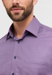 Lila karierte Hemd mit Button-Down-Kragen, marineblauen Knöpfen und einer Brusttasche. Feines, texturiertes Material mit einer strukturierten Passform.