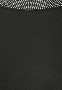 Čierny textilný top s okrúhlym výstrihom, ktorý je ozdobený ozdobným vzorom malých jasných kryštálikov po hornej časti.