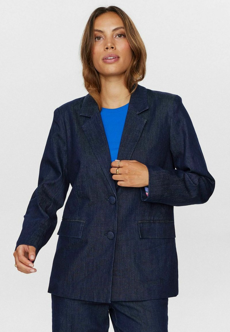 Dark denim blazer with a structured design, notched lapels, two buttons, and side pockets, paired with a blue shirt underneath.
