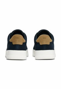 Navy suede sneakers with tan suede accents and a white rubber sole. Features a logo on the heel and a sleek, low-profile design.