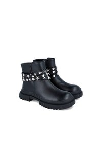 Botas de tobillo de cuero negro con acabado texturizado, decoradas con tachuelas plateadas en forma de estrella y corazón alrededor del tobillo y una suela gruesa.