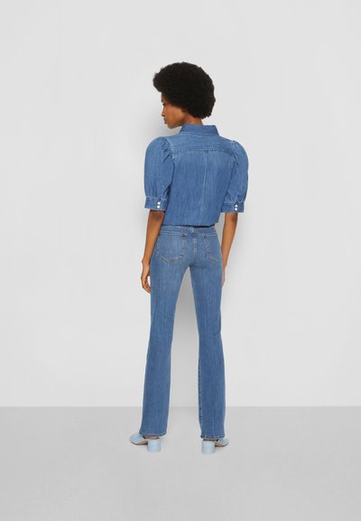 Denim apģērbs ar gaiši zilu puff-sleeve krekliņu un platām biksēm. Audums ir teksturēts, ar aizmugurējām kabatām un gaiši ziliem papēžiem.