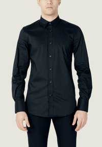 Camicia da uomo nera a maniche lunghe con colletto button-down, texture liscia, design aderente e bottoni neri sulla parte anteriori e sui polsini.