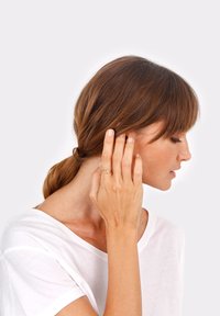 Goldener Ring an einer Hand mit wellenförmigem Design. Der Hintergrund ist neutral, der Fokus liegt auf dem Ring und der Hand, die sich in der Nähe des Ohrs befindet.