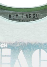 Colletto della maglietta con bordo verde, nome del marchio "KEY LARGO" stampato all'interno e grafica parziale blu e bianca con testo su tessuto chiaro.