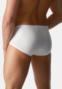 Weiße Baumwollunterwäsche mit glatter Textur, elastischem Bund und enganliegendem Schnitt, der den Rücken und den oberen Oberschenkelbereich zeigt.
