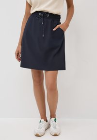 Jupe de sport marine en tissu léger, avec une taille élastique à cordon de serrage, des poches latérales et une finition lisse.
