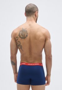 Cuecas boxer azul-marinho com cintura elástica vermelha e marca "JACK & JONES". Textura suave, design ajustado e estilo minimalista.