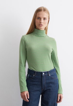Grün-weißer gestreifter Rollkragenpullover mit langen Ärmeln, kombiniert mit dunkelblauen Jeans. Glatter Stoff, taillierte Passform.