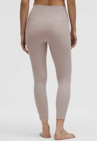 Jasnoróżowe legginsy wykonane z elastycznego materiału, z wysokim stanem, gładką teksturą i bez widocznych wzorów czy elementów metalowych.
