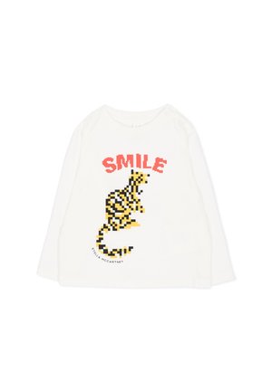 Balti ilgomis rankovėmis marškiniai su pikseliuota geltono ir juodo tigro grafika ir raudonu tekstu "SMILE" virš tigro.