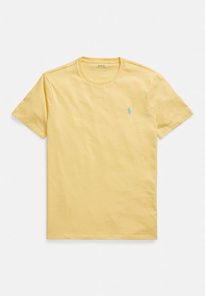 Žluté bavlněné tričko s kulatým výstřihem, krátkými rukávy a malým tyrkysovým logem polo na levé straně hrudi. Hladká textura.