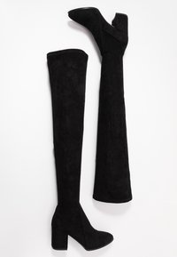 Schwarze Overknee-Stiefel aus weichem Wildleder, mit einem klobigen Absatz und einer runden Zehenpartie, die eine glatte Textur und ein nahtloses Design aufweisen.