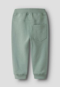 Ljusgröna barnbyxor i sweatshirtmodell med elastisk midja, ribbade fotmanchetter och en enda ficka på baksidan till höger.