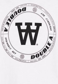 Bílý tričko s velkým kulatým černým grafikem s textem "DOUBLE A" a stylizovaným "W", spolu s technickými parametry pneumatik a brandingovými detaily.