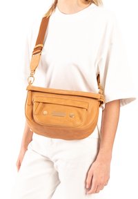 Leren schoudertas in tan kleur met een gladde textuur, een voorzak met rits, gouden hardware accenten en een lange verstelbare schouderband.
