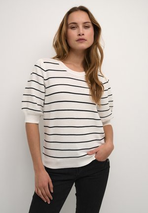 Pull en tricot rayé blanc avec des rayures horizontales noires. Col côtelé et manches courtes bouffantes. Associé à un jean noir.