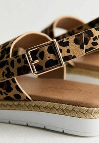 Sandaler med leopardmönster och bred rem, guldfärgad spänne och juteomsluten mellansula. Dämpad innersula med en vit gummiyttersula.